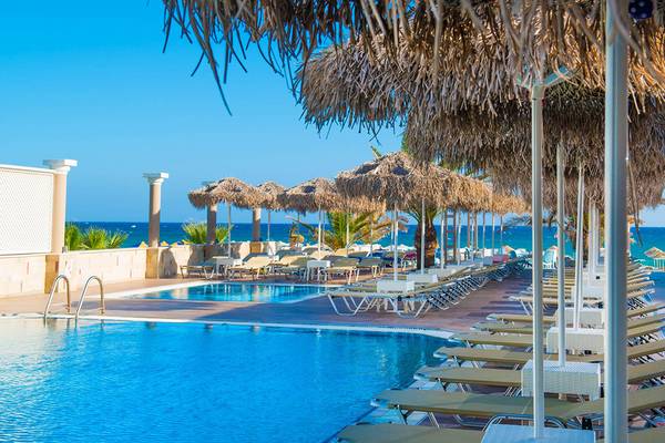 Pool und Liegestühle im Odyssia Beach Hotel mit Blick auf das Meer