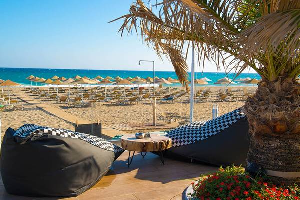 Ausblick auf den Strandbereich des Odyssia Beach Hotels mit Lounge-Sesseln und Sonnenschirmen.