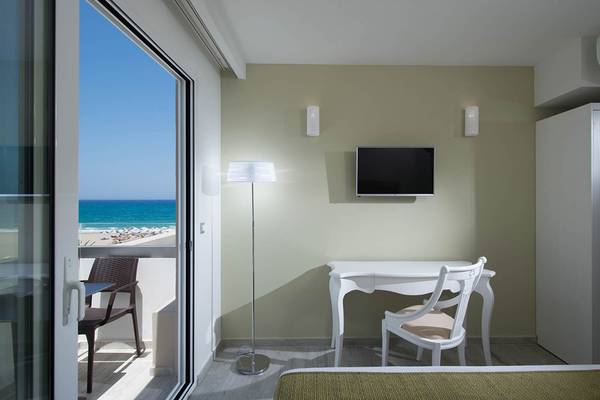 Innenansicht eines Zimmers im Odyssia Beach Hotel mit Blick auf den Balkon und das Meer.