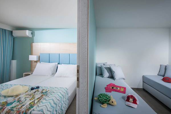 Doppelzimmer-Innenansicht im Odyssia Beach Hotel mit zwei Betten, blauen Wänden und hellem Dekor.