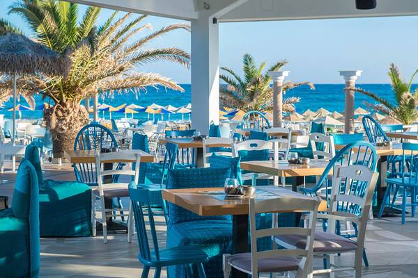 Terrasse des Odyssia Beach Hotels mit Tischen und Stühlen am Strand