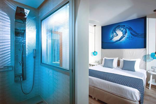 Schlafzimmer und Badezimmer im Odyssia Beach Hotel mit blauem Thema und modernen Möbeln.