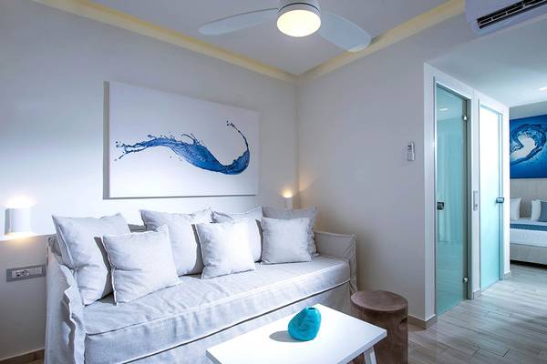 Wohnbereich des Odyssia Beach Hotels mit Schlafsofa, Tisch, Gemälde und Schlafzimmer