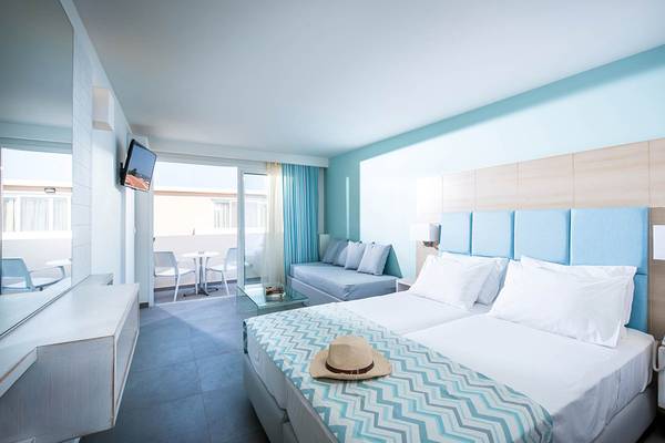 Innenansicht eines Zimmers im Odyssia Beach Hotel mit Doppelbett, Sofa, Fernseher und Balkon