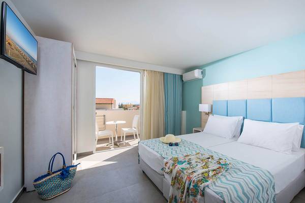 Doppelzimmer im Odyssia Beach Hotel mit Blick auf den Balkon und die Terrasse.