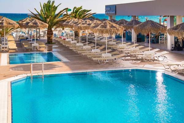 Außenpoolbereich des Odyssia Beach Hotels mit Liegestühlen und Sonnenschirmen.