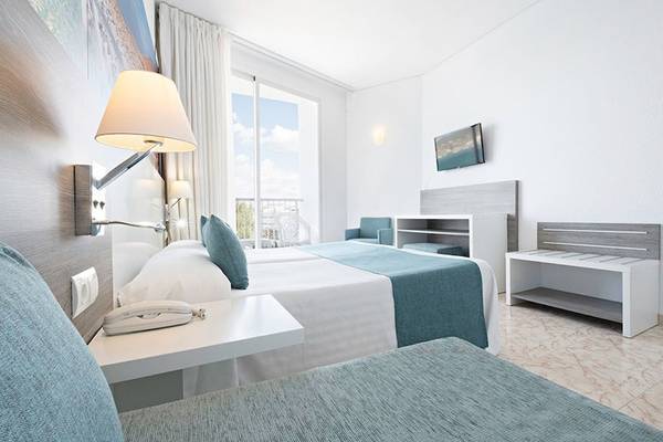 Ein modernes Hotelzimmer im Azuline Hotel Mar Amantis mit Doppelbett, Schreibtisch und Balkonzugang.