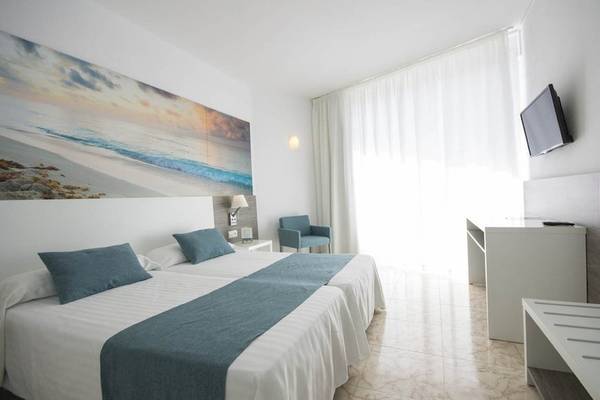Innenansicht eines Doppelzimmers im Azuline Hotel Mar Amantis mit zwei Betten, Kissen und einem Fernseher an der Wand.