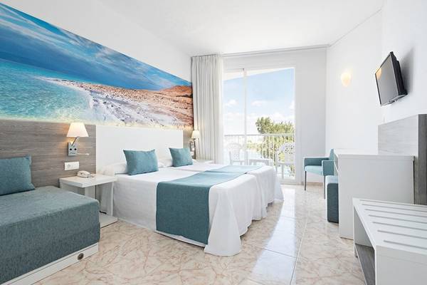Innenansicht eines Hotelzimmers mit zwei Betten, Balkon und moderner Einrichtung.