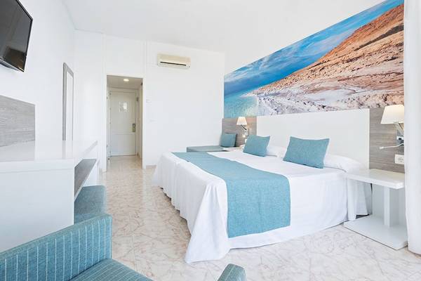 Hotelzimmer im Azuline Hotel Mar Amantis mit weißem Bett, blauen Kissen und Wandbild.