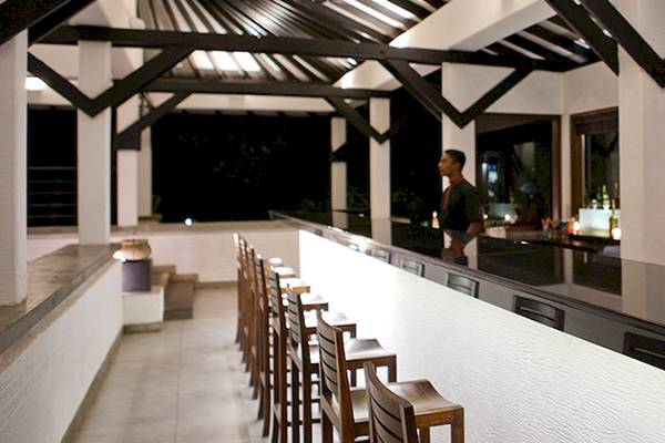Innenansicht der Bar im Club Hotel Dolphin mit Thekenbereich und hohen Stühlen.
