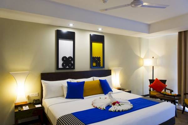 Schlafzimmer im Club Hotel Dolphin mit großem Bett, dekorativen Kissen und Nachttischen.