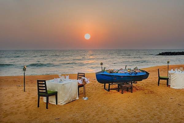 Strand mit Tisch am Abend vor dem Club Hotel Dolphin mit Blick auf den Ozean und den Sonnenuntergang.