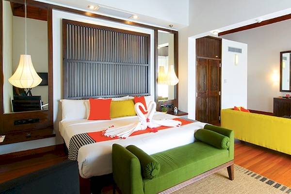 Innenansicht eines Zimmers im Club Hotel Dolphin mit einem großen Bett, zwei Sofas, und verschiedenen Dekorelementen.