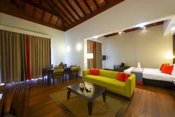 Innenansicht der Suite im Club Hotel Dolphin mit grünem Sofa, Tisch und Bett.