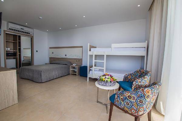 Doppelbett-Zimmer im Stamatia Hotel mit einem Einzelbett, einem Etagenbett und einem Tisch mit Blumen.