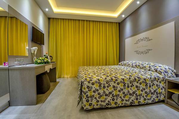 Schlafzimmer im Stamatia Hotel mit Doppelbett, gelben Vorhängen und moderner Einrichtung.