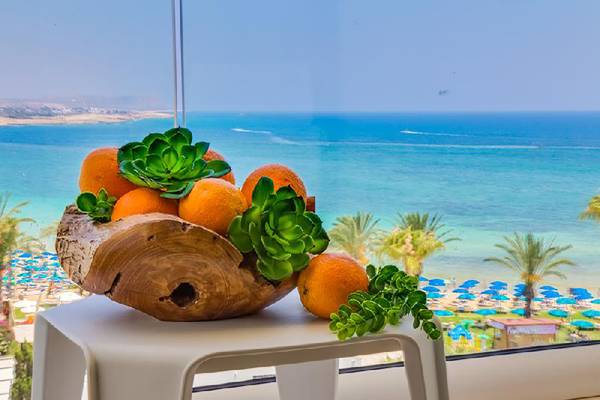 Blick aus dem Fenster auf Orangen in einem Holzschal vor dem Meer