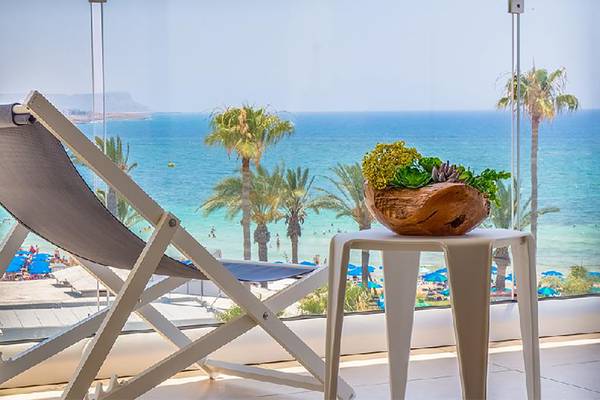 Aussicht von der Terrasse des Stamatia Hotels auf das Meer mit Palmen und einem Tisch mit einer Pflanze.