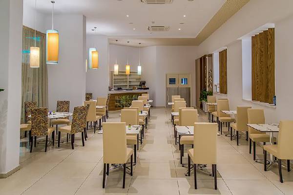 Innenbereich des Stamatia Hotels, ein Restaurant mit runden Tischen und Stühlen, geometrischem Muster und heller Beleuchtung.