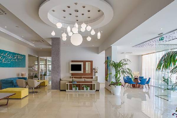 Innenansicht der Lobby des Stamatia Hotels mit modernen Möbeln, Pflanzen und einer großen Deckenleuchte.