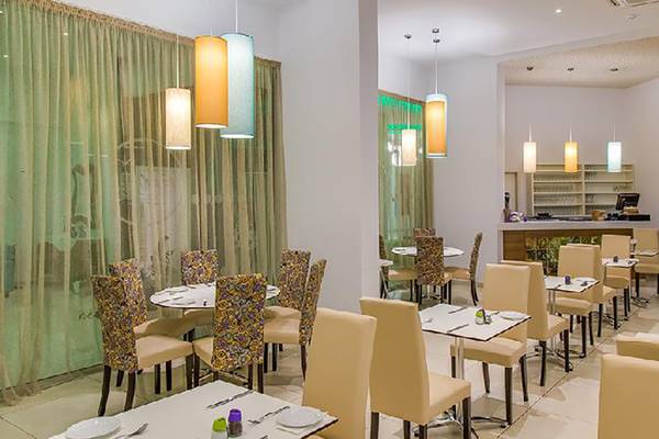 Innenansicht des Restaurants im Stamatia Hotel mit runden Tischen und cremefarbenen Stühlen.