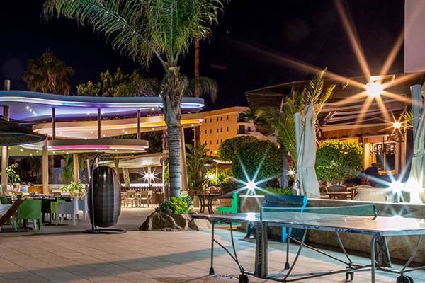 Stamatia Hotel Außenbereich bei Nacht mit farbigen Beleuchtung, bunten Pflanzen, Tischen und Stühlen.