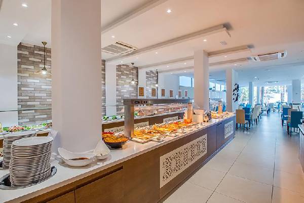 Innenansicht des Buffet-Restaurants im Stamatia Hotel mit vielen Speisen, Tellern und Stühlen.