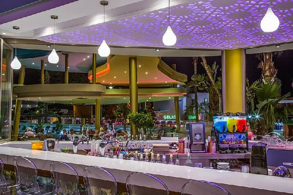 Innenansicht der Bar im Stamatia Hotel mit violetten Deckenleuchten und Glasmöbeln.