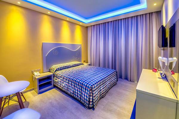 Zimmer im Stamatia Hotel mit blauem und gelbem Dekor, Doppelbett und Fernseher.
