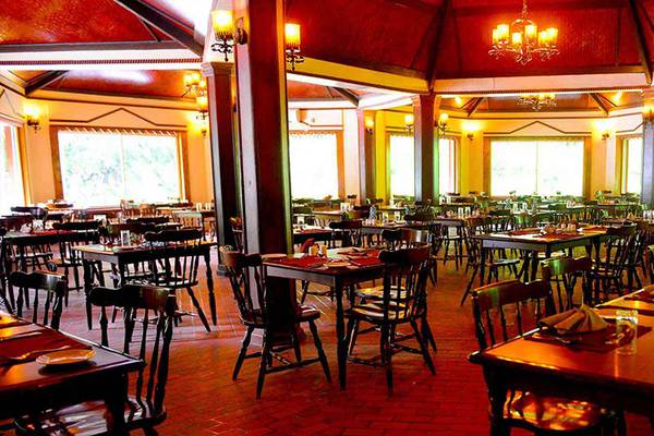 Ein Restaurant des Biyadhoo Island Resorts mit vielen Tischen und Stühlen, Deckenlampen und großen Fenstern.