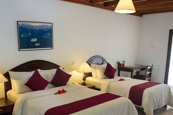 Doppelzimmer im Biyadhoo Island Resort mit zwei Betten, Nachttischen, Lampen und einem Gemälde an der Wand.