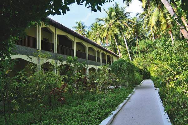Eingang zum Biyadhoo Island Resort, umgeben von Bäumen und Pflanzen.