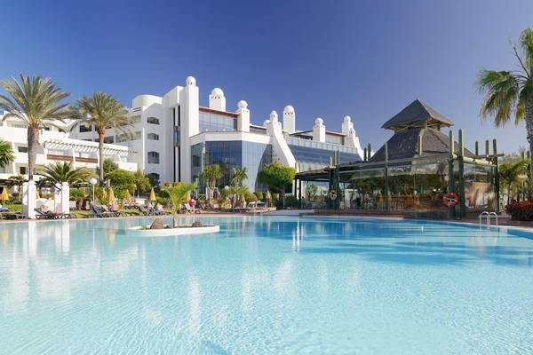 Außenpool des H10 Timanfaya Palace Hotels mit weißen Gebäuden und Palmen