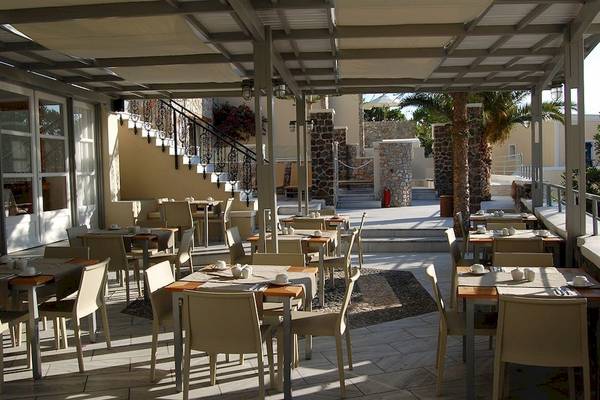 Terrassenrestaurant im Freien mit Tischen und Stühlen unter einer Überdachung im Antinea Suites & Spa