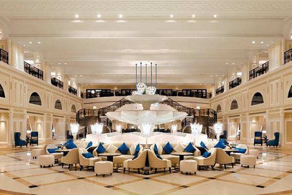 Lobby des Waldorf Astoria Ras Al Khaimah mit zentralem Wasserbrunnen und blauen Sitzgelegenheiten.