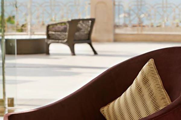 Loungebereich des Waldorf Astoria Ras Al Khaimah mit zwei Stühlen und einem Tisch vor einer Glaswand.
