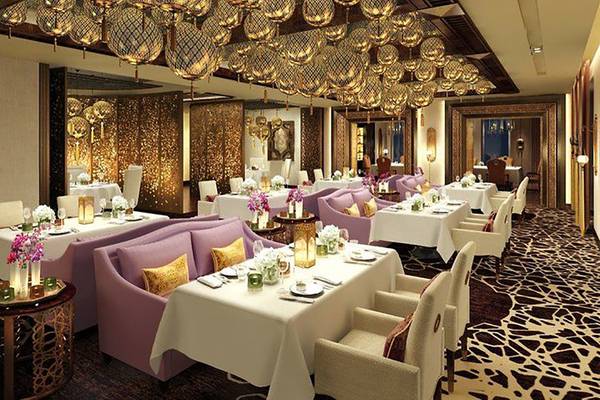Innenansicht des Restaurants im Waldorf Astoria Ras Al Khaimah mit hängenden Lampen und gedeckten Tischen.