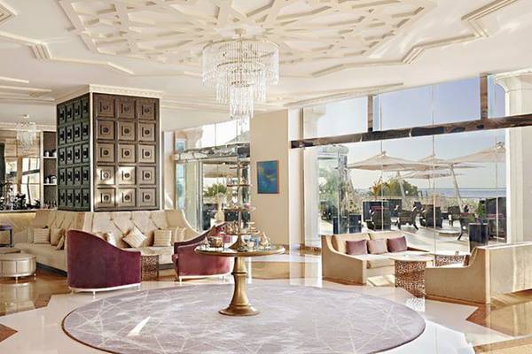 Lobby des Waldorf Astoria Ras Al Khaimah mit Möbeln, Kronleuchter und Meerblick.
