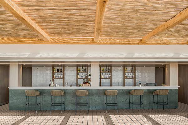 Bar-Terrasse im Mitsis Norida Beach Hotel mit Holzsäulen und Weinfässern.