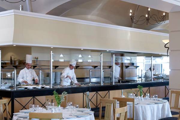 Im Mitsis Norida Beach Hotel Restaurant sehen wir ein Buffet mit Köchen, die hinter einer Glaswand arbeiten.