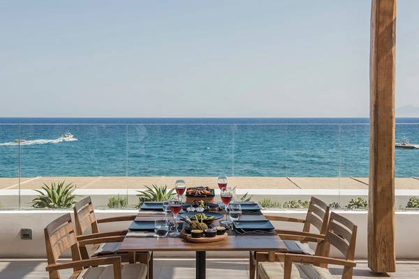 Terrasse des Mitsis Norida Beach Hotels mit Blick auf das Meer und zwei Boote auf dem Wasser.