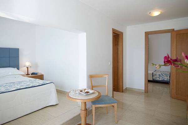 Schlafzimmer im Mitsis Norida Beach Hotel mit Bett, Tisch und Stuhl.