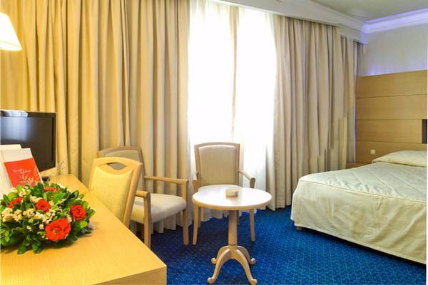 Hotelzimmer im El Mouradi Mahdia mit Bett, Schreibtisch, Stühlen und Blumen.