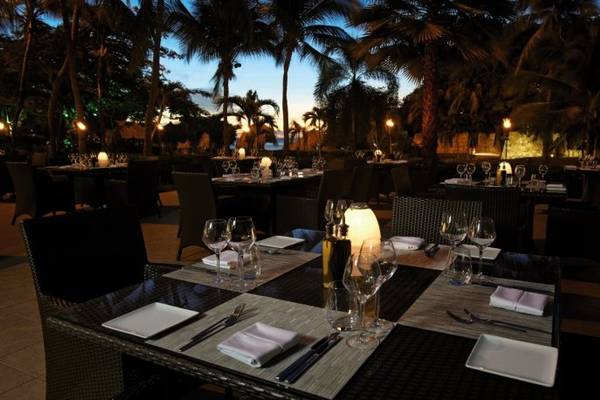 Abendessen im Hotel Dreams Curacao Resort, Spa & Casino mit stimmungsvoller Beleuchtung und Blick auf Palmen und Meer.