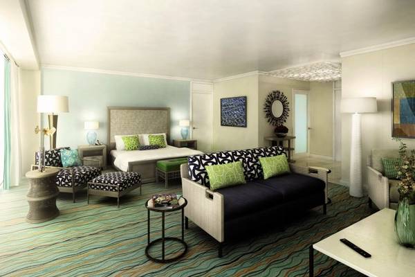 Suite-Zimmer im Dreams Curacao Resort mit großem Bett, Wohnzimmersofa und modernen Möbeln.