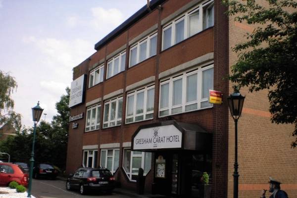 Außenansicht des Gresham Carat Hotels mit einer Person, die auf einer Bank vor dem Gebäude sitzt