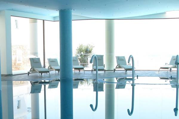 Poolbereich im Atrium Prestige Thalasso Spa Resort & Villas mit Liegestühlen und Panoramafenstern.
