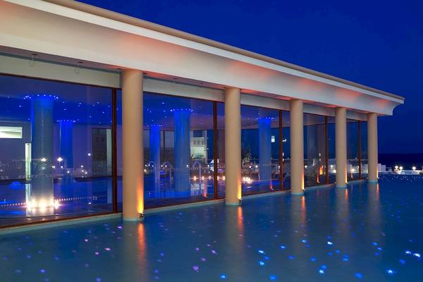 Nachtansicht des Atrium Prestige Thalasso Spa Resort Pools mit blauen Lichtern und Säulen.
