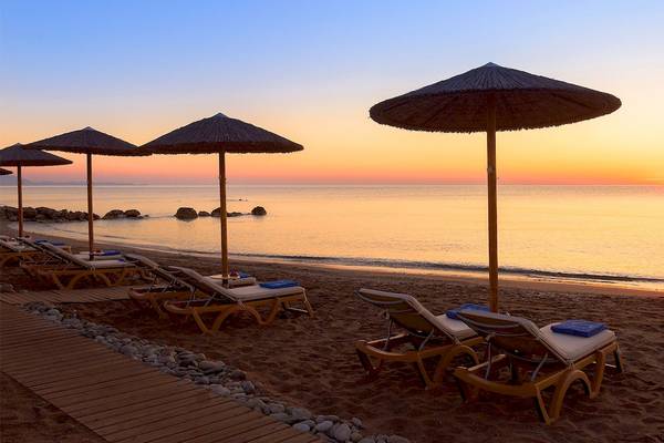 Strand mit Sonnenliegen und Sonnenschirmen bei Sonnenuntergang